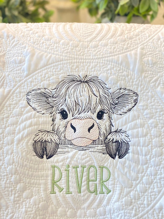 Close-up of an embroidered peeking highland cow with delicate stitching on a quilted white fabric, personalized with the name River on the Personalized Embroidered Peeking Highland Cow Baby Quilt | Custom Name Heirloom Blanket.