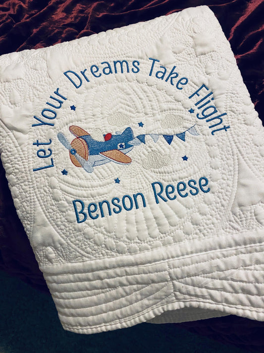Personalized "Let Your Dreams Take Flight" Airplane Baby Quilt | Custom Name Blanket | Heirloom Keepsake featuring embroidered blue airplane and custom name Benson Reese on white quilted fabric.