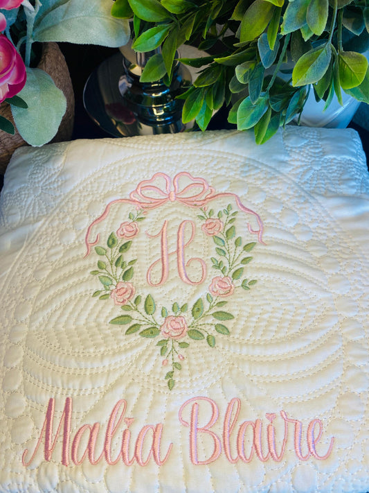 Personalized Rose Vine Bow Crest Monogram Baby Quilt | Custom Embroidered Heirloom Blanket featuring delicate pink rose vine embroidery, a monogrammed initial, and the name Malia Blaire in elegant script.