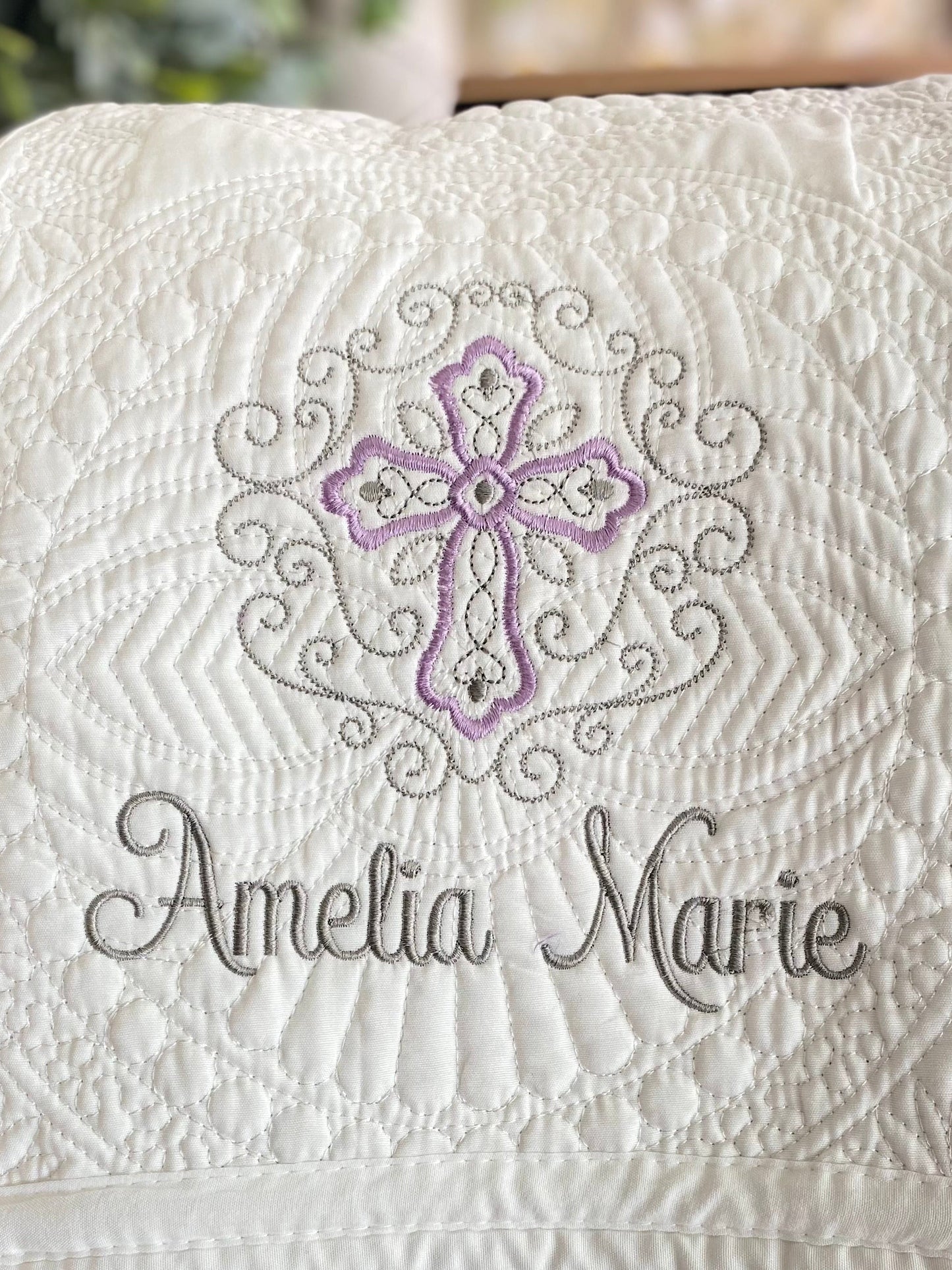 Personalized Lavender Filigree Cross Baby Quilt | Custom Name Christening Heirloom Blanket for Girls featuring intricate lavender and gray embroidery with the name Amelia Marie on a white quilted fabric.