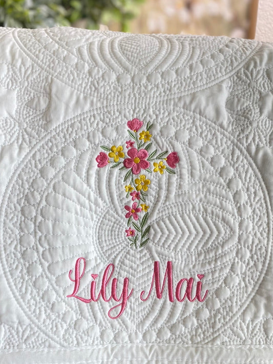 Personalized Floral Cross Baptism Baby Quilt | Custom Name Christening Heirloom Blanket for Girls featuring intricate white quilting with embroidered pink and yellow floral cross and custom name Lily Mai.