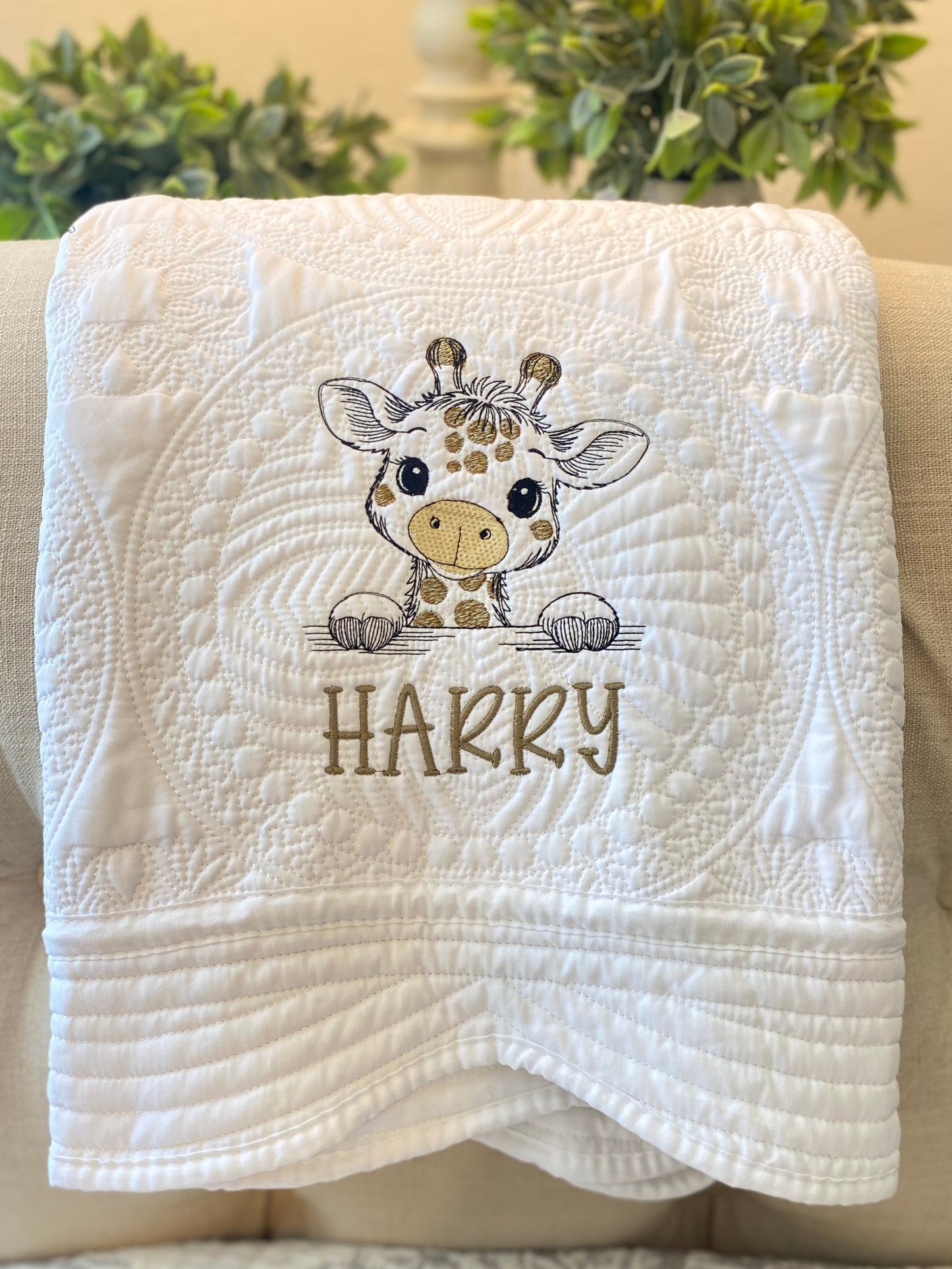 Close-up of a white quilt featuring a cute embroidered giraffe and the name Hakky, showcasing the Personalized Embroidered Giraffe Baby Quilt | Custom Name Heirloom Blanket as a charming handmade baby shower and newborn gift.