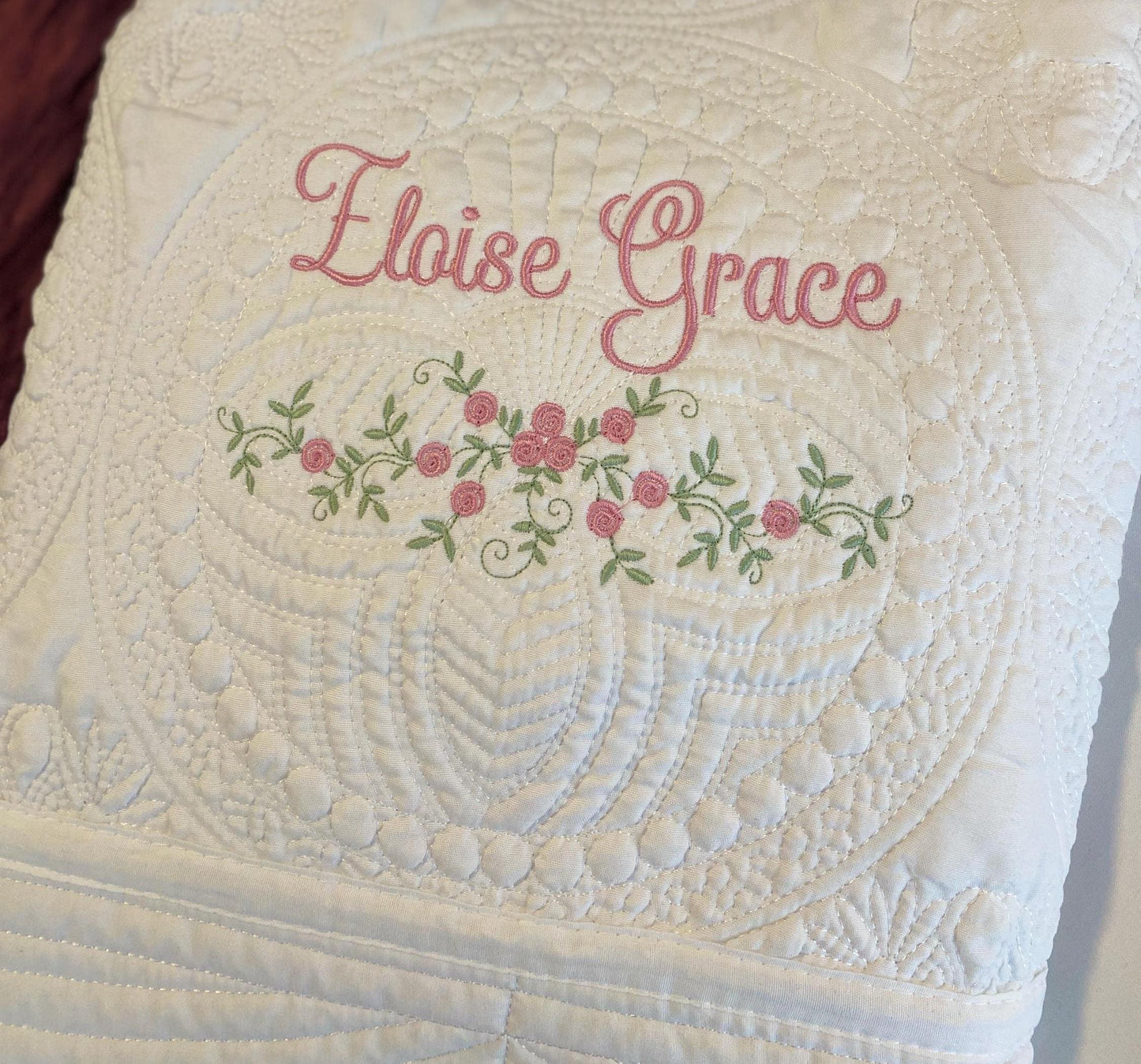 Personalized Delicate Floral Rose Swag Baby Quilt | Custom Embroidered Heirloom Blanket featuring soft white quilting with delicate pink rose floral embroidery and custom name stitching.
