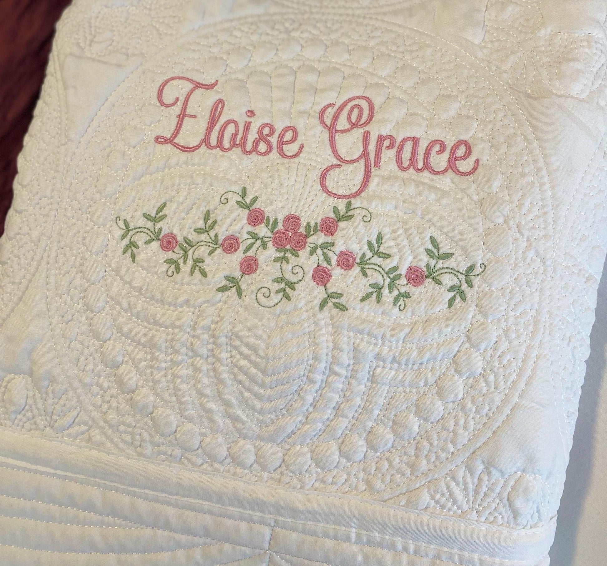 Personalized Delicate Floral Rose Swag Baby Quilt | Custom Embroidered Heirloom Blanket featuring soft white quilting with delicate pink rose floral embroidery and custom name stitching.