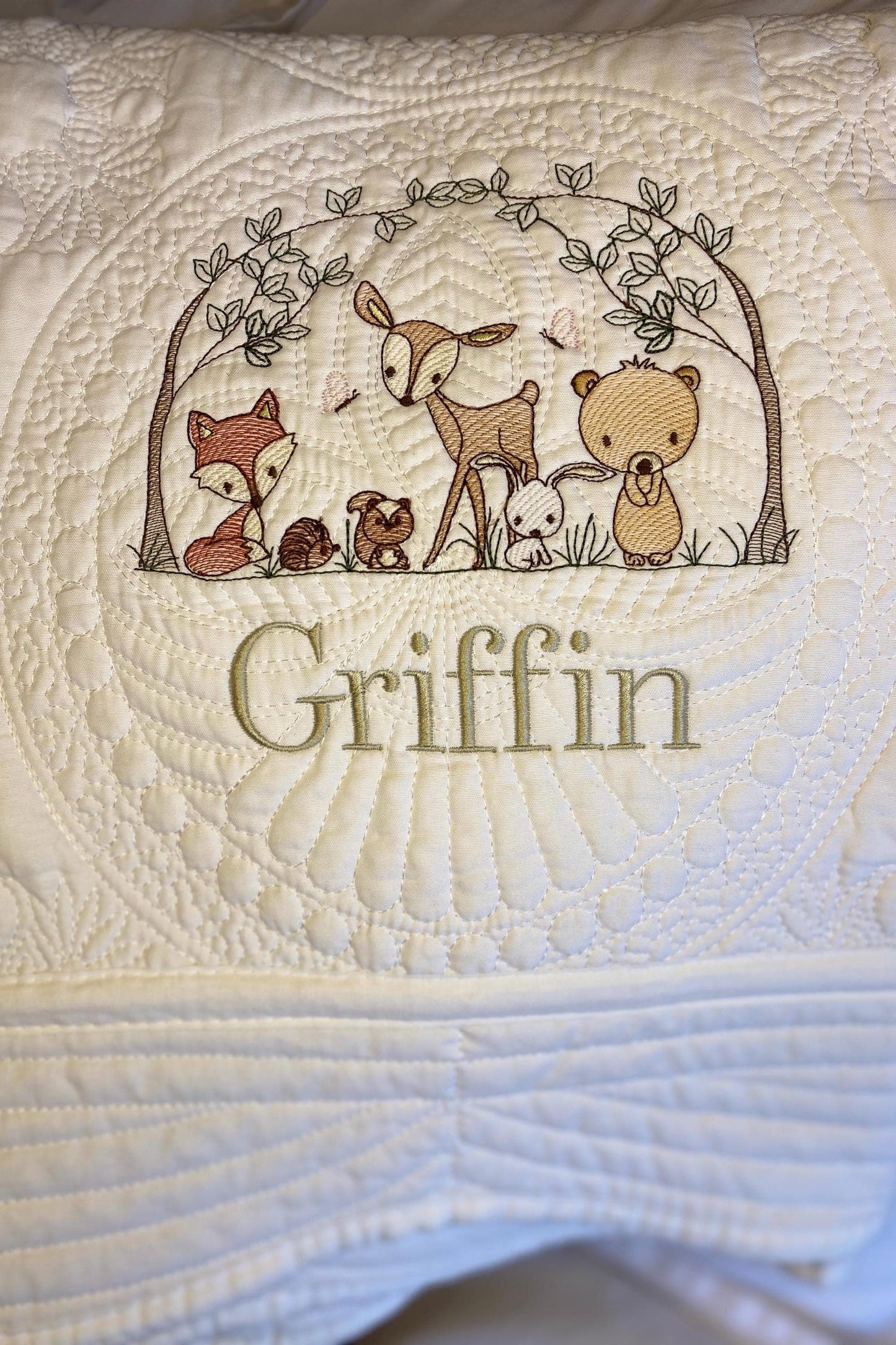 Personalized Woodland Animals Baby Quilt | Custom Name Heirloom Blanket for Boys & Girls featuring embroidered forest animals and the name Griffin on a soft, quilted cream fabric.