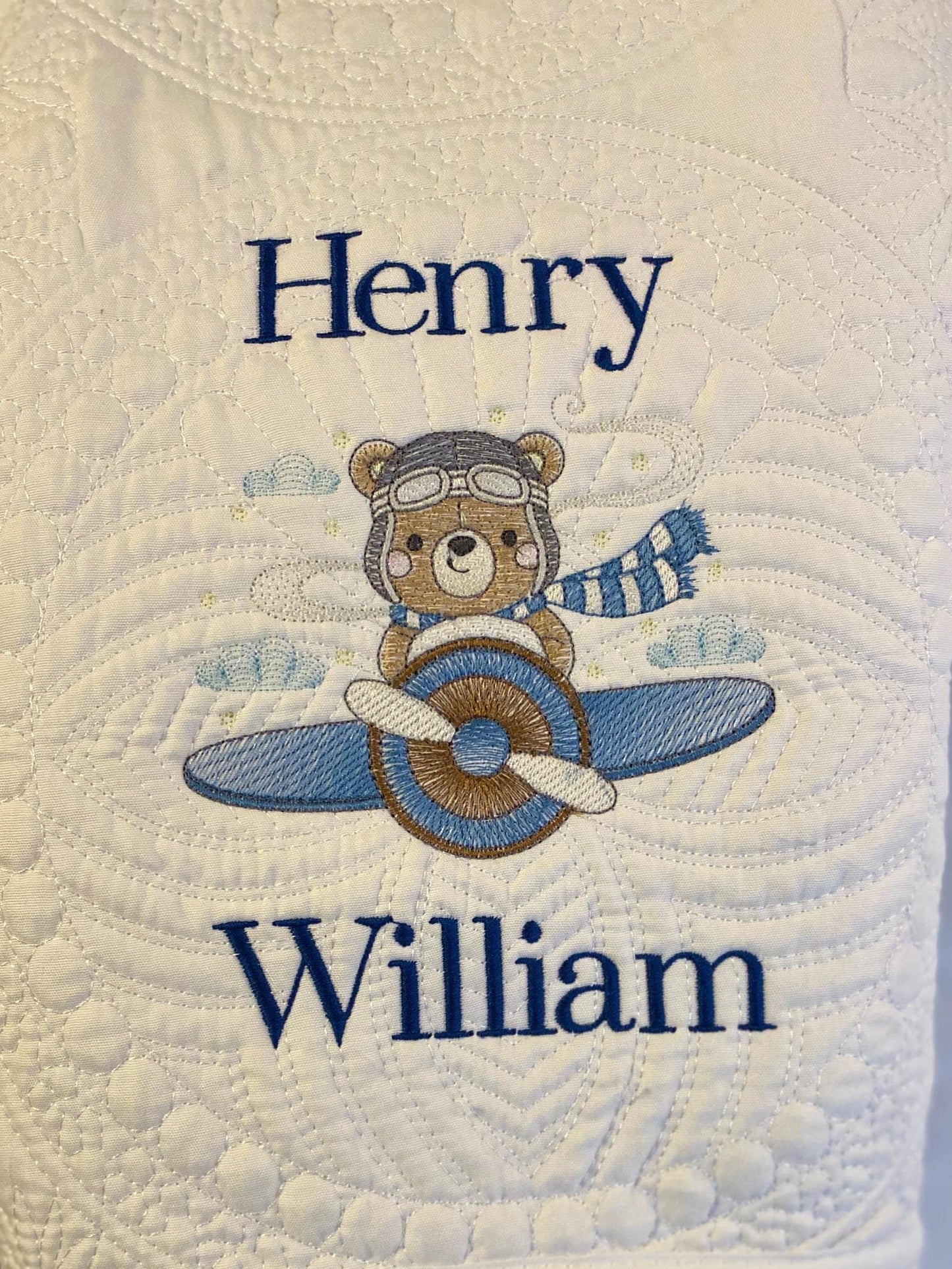 Personalized Bear Pilot Airplane Baby Quilt | Custom Name Heirloom Blanket featuring embroidered bear pilot with airplane and custom name "Henry William" on a quilted white background.