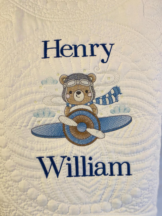 Personalized Bear Pilot Airplane Baby Quilt | Custom Name Heirloom Blanket featuring embroidered bear pilot with airplane and custom name "Henry William" on a quilted white background.