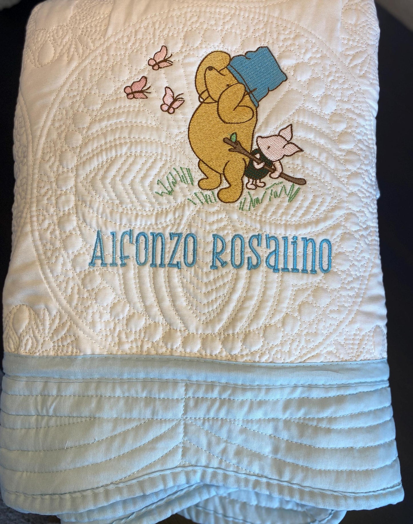 Personalized Storybook Bear & Friend with Bees Baby Quilt | Custom Name Heirloom Keepsake showing a cozy quilt with embroidered bear in a blue hat, small friend, bees, and custom name "Alfonzo Rosalino" in blue thread.