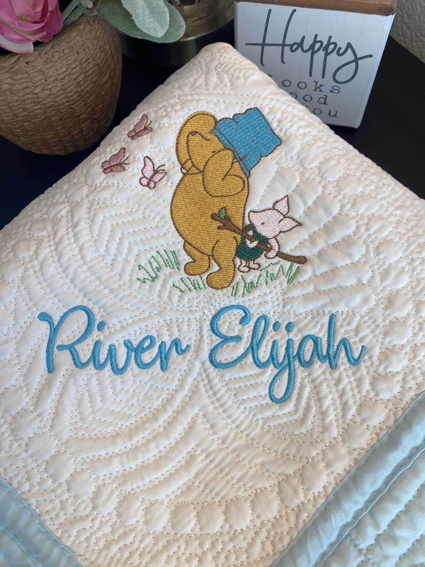 Personalized Storybook Bear & Friend with Bees Baby Quilt | Custom Name Heirloom Keepsake featuring embroidered bear, friend, and butterflies with custom name River Elijah on a quilted soft cream background.