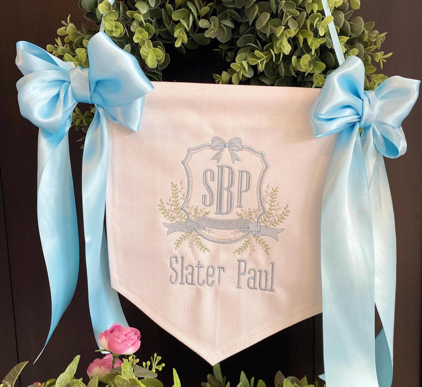 Personalized Embroidered Baby Birth Announcement Banner | Hospital Door & Bassinet Sign featuring soft blue satin bows and delicate embroidered initials with name on pale fabric.