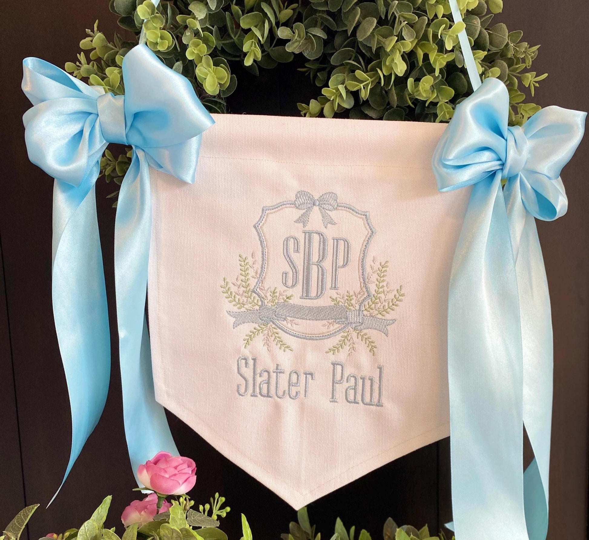 Personalized Embroidered Baby Birth Announcement Banner | Hospital Door & Bassinet Sign featuring soft blue satin bows and delicate embroidered initials with name on pale fabric.