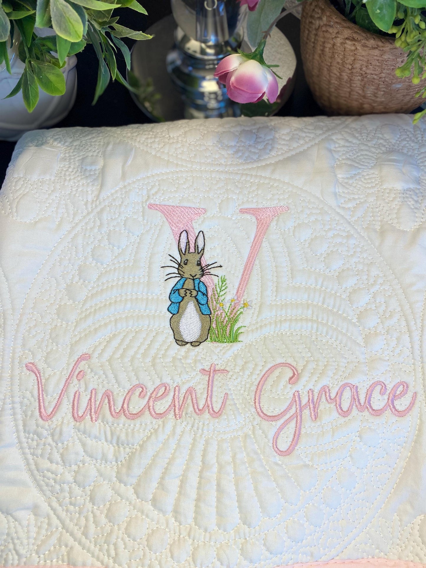 Personalized Embroidered Bunny Baby Quilt | Classic Storybook Heirloom Keepsake | Custom Name Blanket featuring delicate pink script name and a charming embroidered bunny with floral accents on soft white quilted fabric.