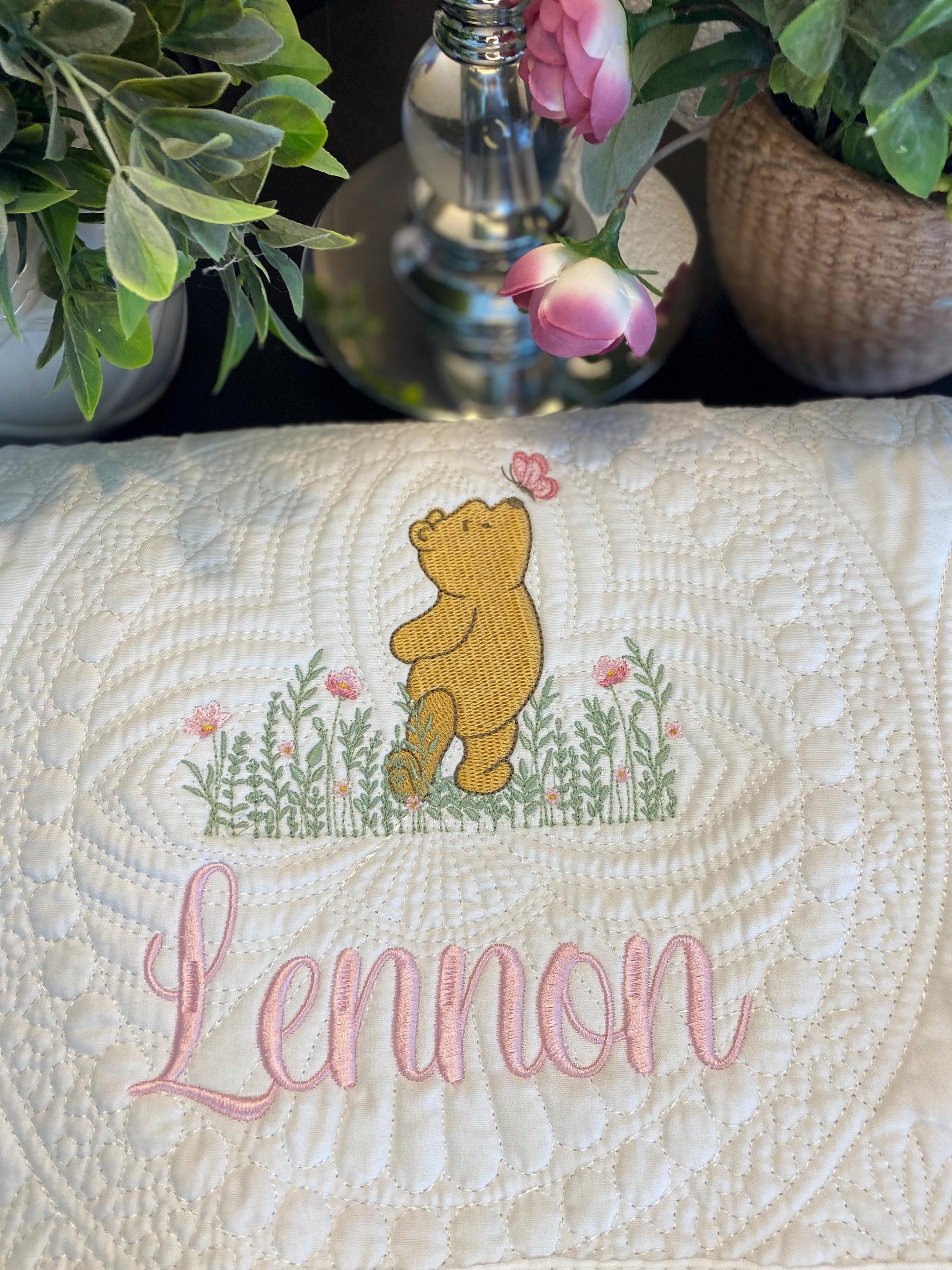 Personalized Classic Pooh Bear Meadow & Butterfly Baby Quilt | Custom Name Heirloom Blanket featuring embroidered Pooh Bear with pink butterfly above green meadow and custom name Lennon in soft pink script.