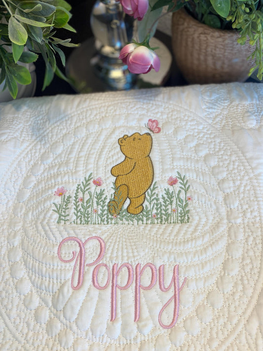 Embroidered baby blanket featuring a classic Pooh bear walking among meadow flowers with a butterfly, personalized with the name Poppy on the Personalized Classic Pooh Bear Meadow & Butterfly Baby Quilt | Custom Name Heirloom Blanket.