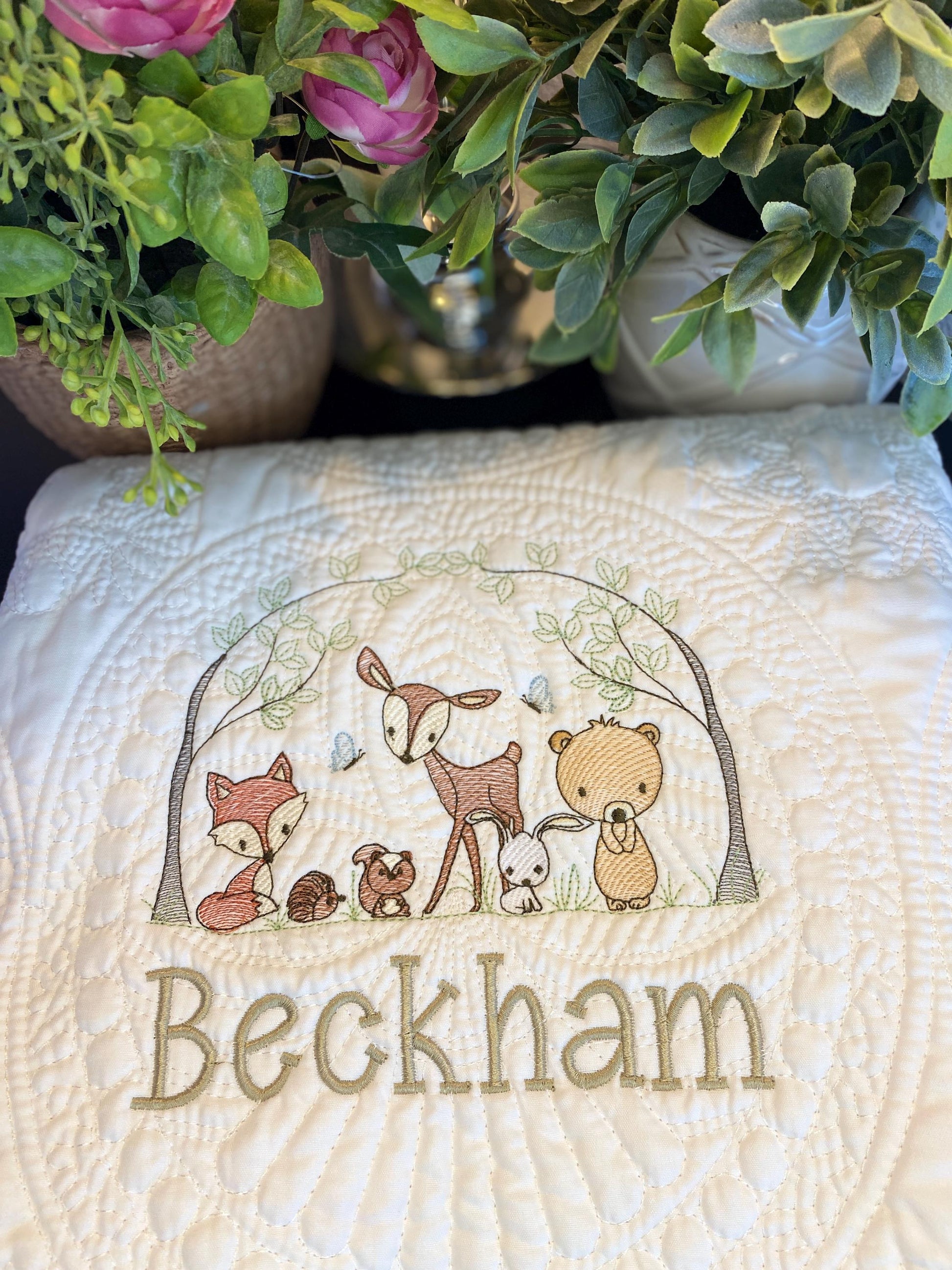 Close-up of an embroidered personalized woodland animals baby quilt featuring a fox, hedgehog, deer, rabbit, and bear under a leafy arch with the custom name Beckham, showcasing the Personalized Woodland Animals Baby Quilt | Custom Name Heirloom Blanket for Boys & Girls.