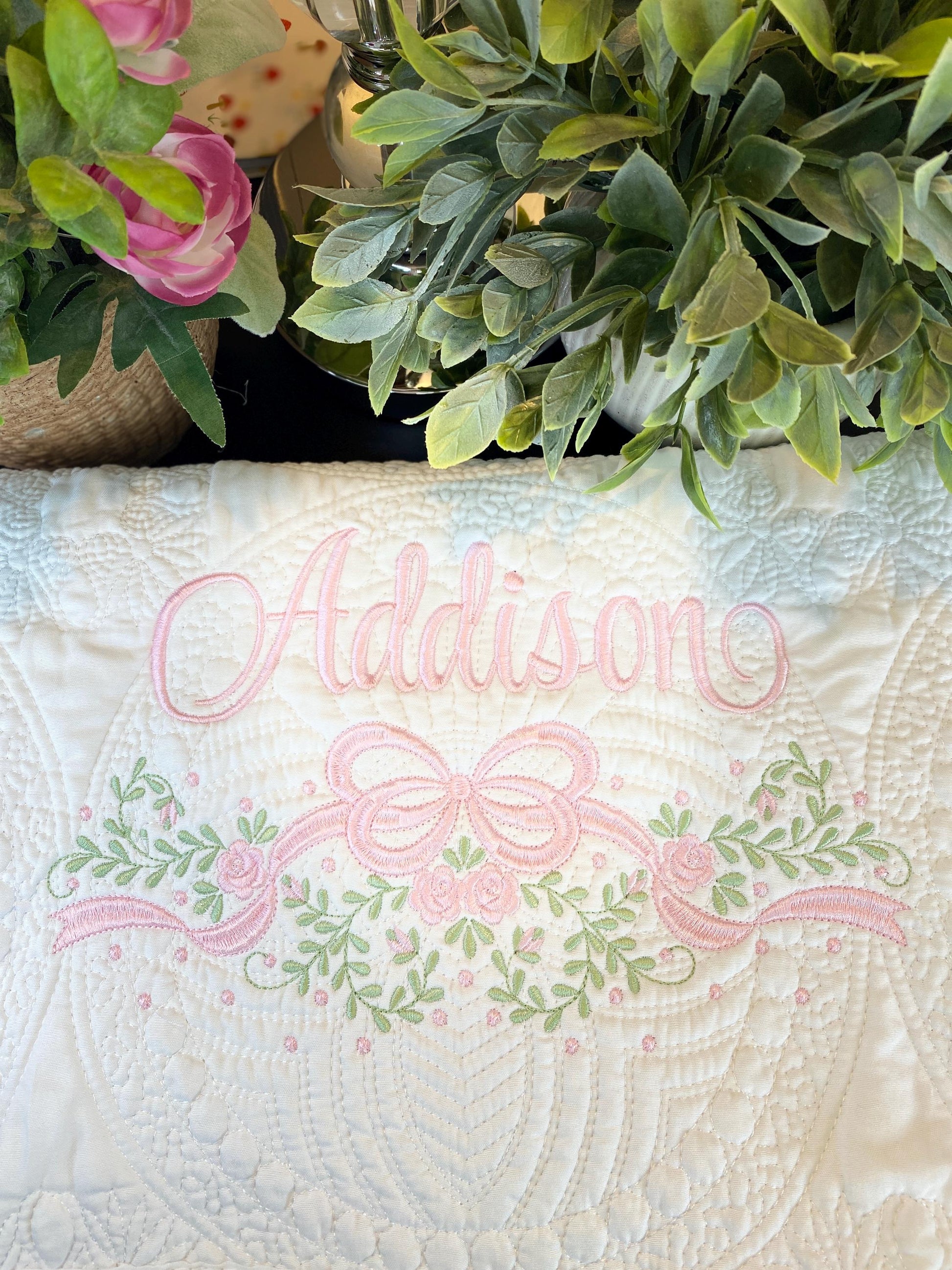Personalized Embroidered Rose Vine & Bow Baby Quilt | Heirloom Keepsake | Custom Name Blanket featuring delicate pink embroidery of the name Addison with floral vine and bow design on a white quilted background.