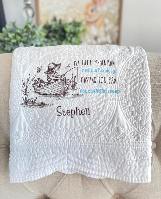 Personalized Little Fisherman Boy & Dog Baby Quilt | Custom Name Heirloom Blanket for Boys featuring an embroidered boy fishing in a boat with a dog and custom name Stephen on a white quilt.