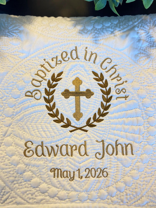 Personalized Baptized in Christ Laurel Cross Baby Quilt | Custom Embroidered Christening Heirloom Blanket featuring gold embroidered cross and laurel design with custom name and date on a white quilted background.