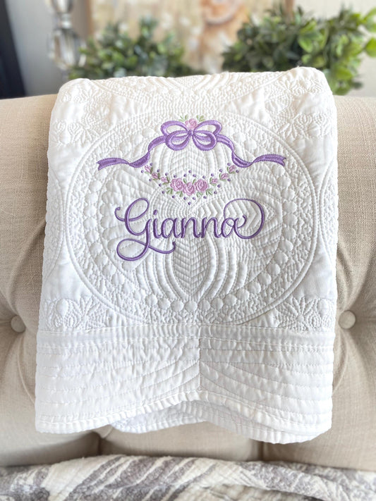 Personalized Floral Vine & Bow Baby Quilt | Custom Name Heirloom Blanket featuring intricate white quilting with a purple embroidered bow, floral vine, and the name Gianna on a soft fabric.