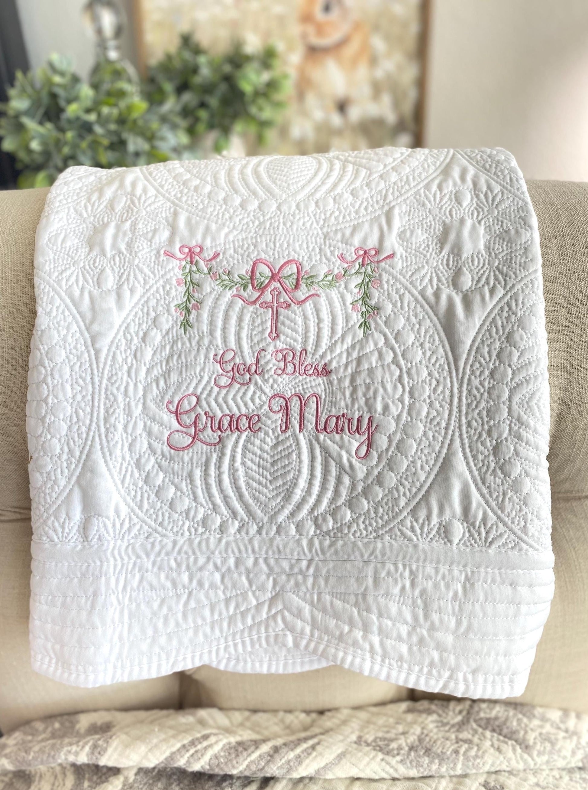 Personalized God Bless Baptism Baby Quilt | Custom Embroidered Christening Heirloom Blanket with delicate pink embroidery and intricate white quilted patterns.