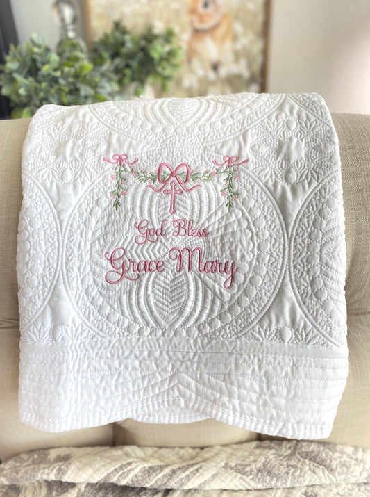 Personalized God Bless Baptism Baby Quilt | Custom Embroidered Christening Heirloom Blanket with delicate pink embroidery and intricate white quilted patterns.