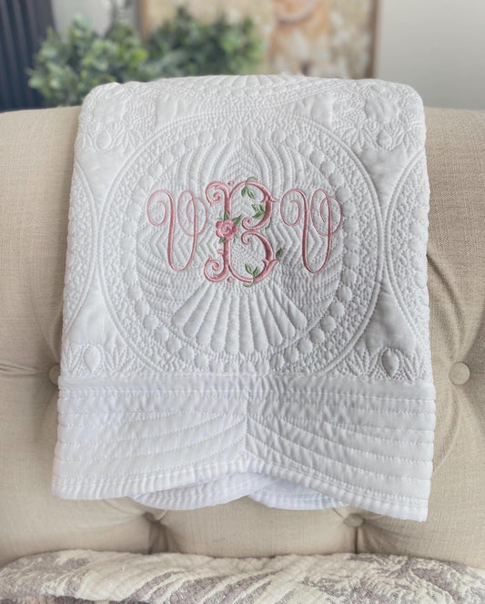 Personalized Vintage Rose Monogram Baby Quilt | Custom Embroidered Heirloom Blanket with delicate pink floral monogram on a white quilted fabric, perfect newborn or baby shower gift.