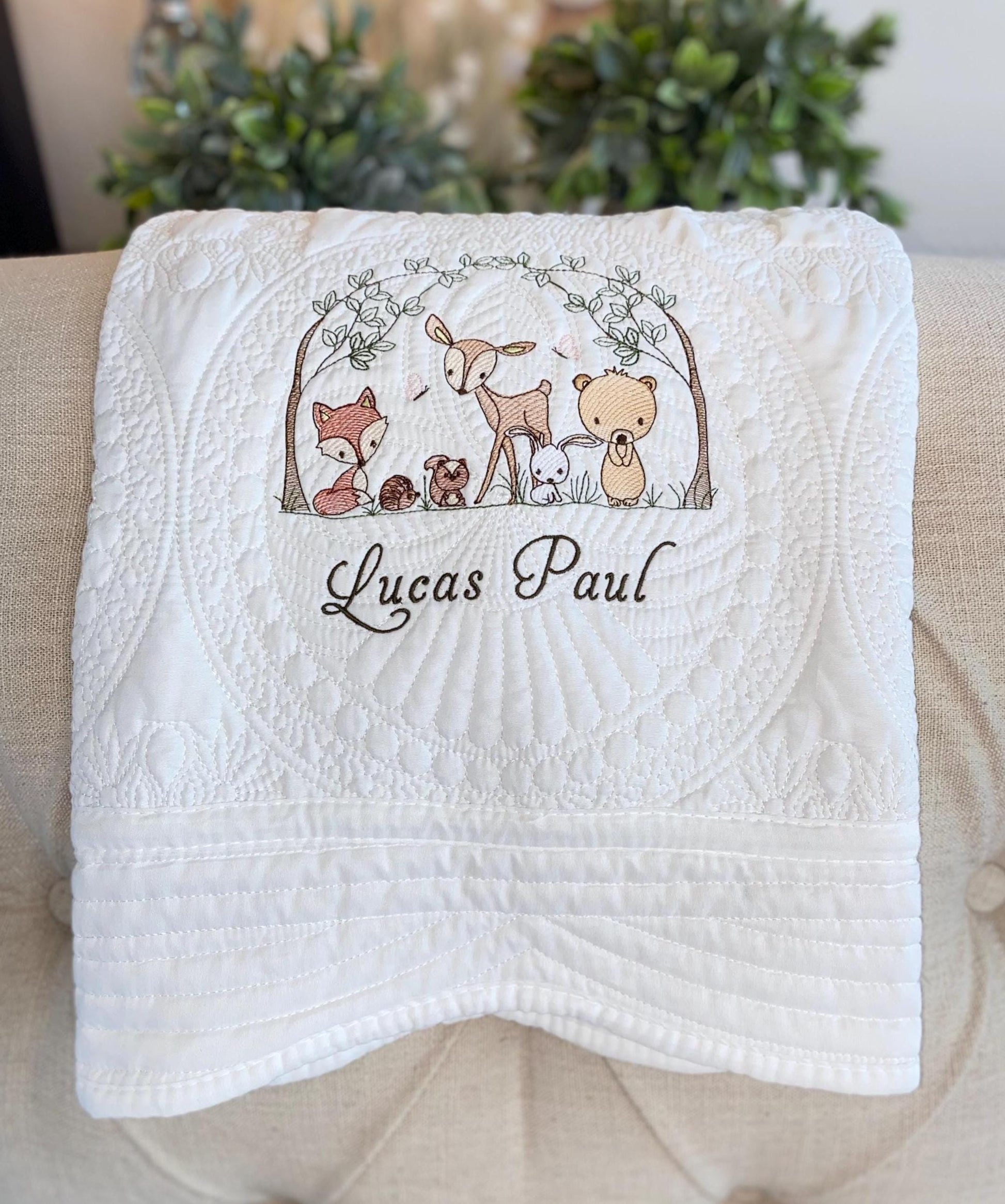 Personalized Woodland Animals Baby Quilt | Custom Name Heirloom Blanket for Boys & Girls featuring embroidered forest animals and the name Lucas Paul on a white quilted fabric.