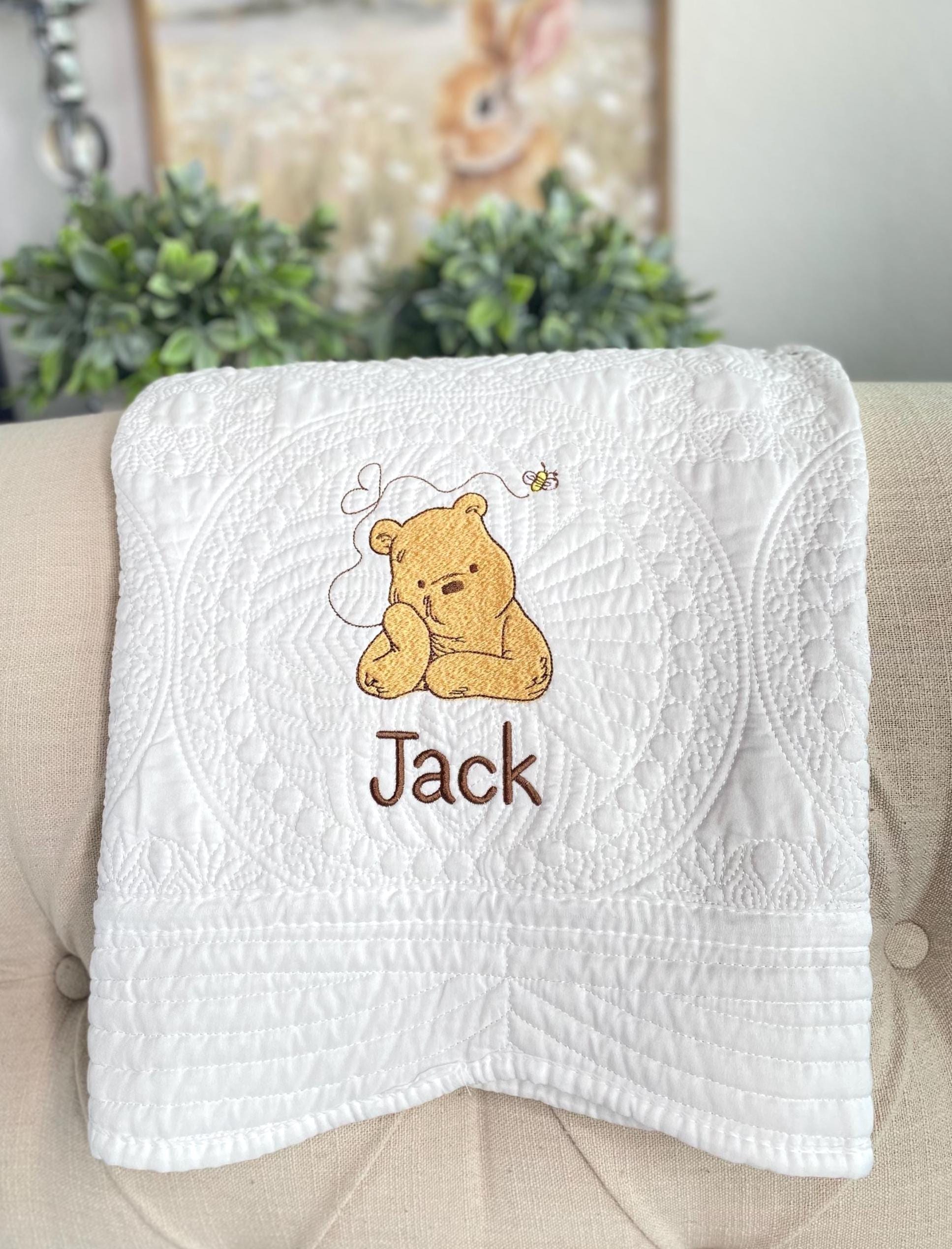 White quilt featuring an embroidered bear with a small bee, personalized with the name Jack, showcasing the Personalized Storybook Bear Honey Bee Baby Quilt | Custom Name Heirloom Keepsake design.