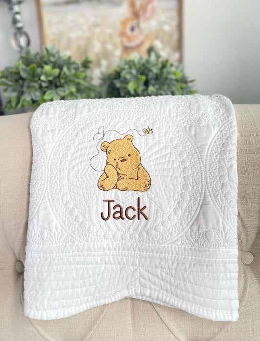 White quilt featuring an embroidered bear with a small bee, personalized with the name Jack, showcasing the Personalized Storybook Bear Honey Bee Baby Quilt | Custom Name Heirloom Keepsake design.