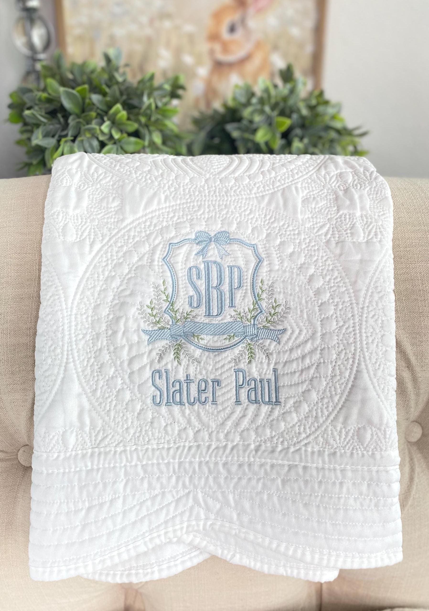 Personalized Vine Crest Monogram Baby Quilt | Custom Embroidered Heirloom Keepsake featuring delicate blue and green embroidery on a textured white quilt, perfect as an heirloom baby gift.