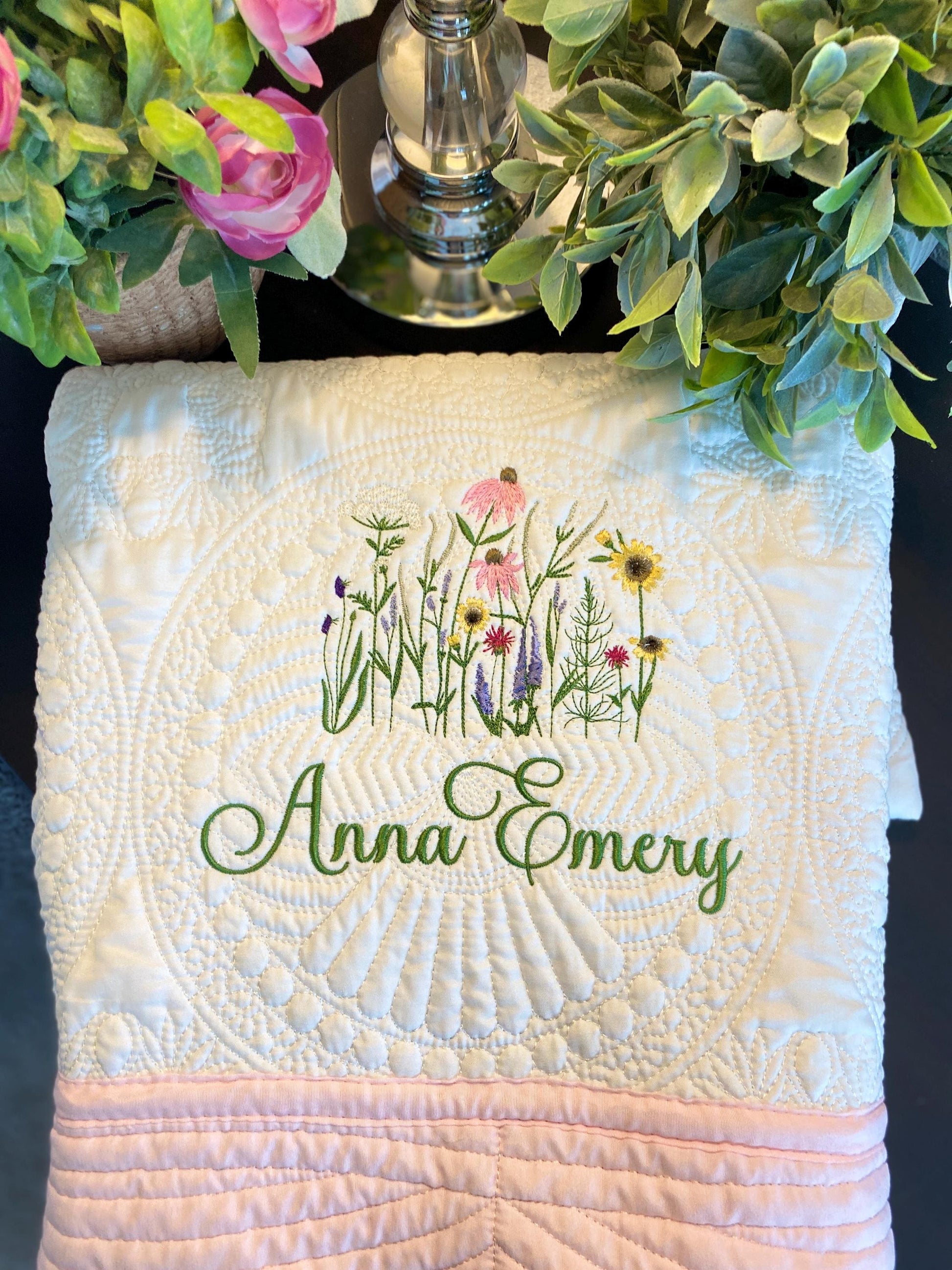 Personalized Wildflower Meadow Baby Quilt | Custom Name Heirloom Blanket for Girls featuring delicate embroidered wildflowers and custom green script name on a textured white quilt with pink edging.