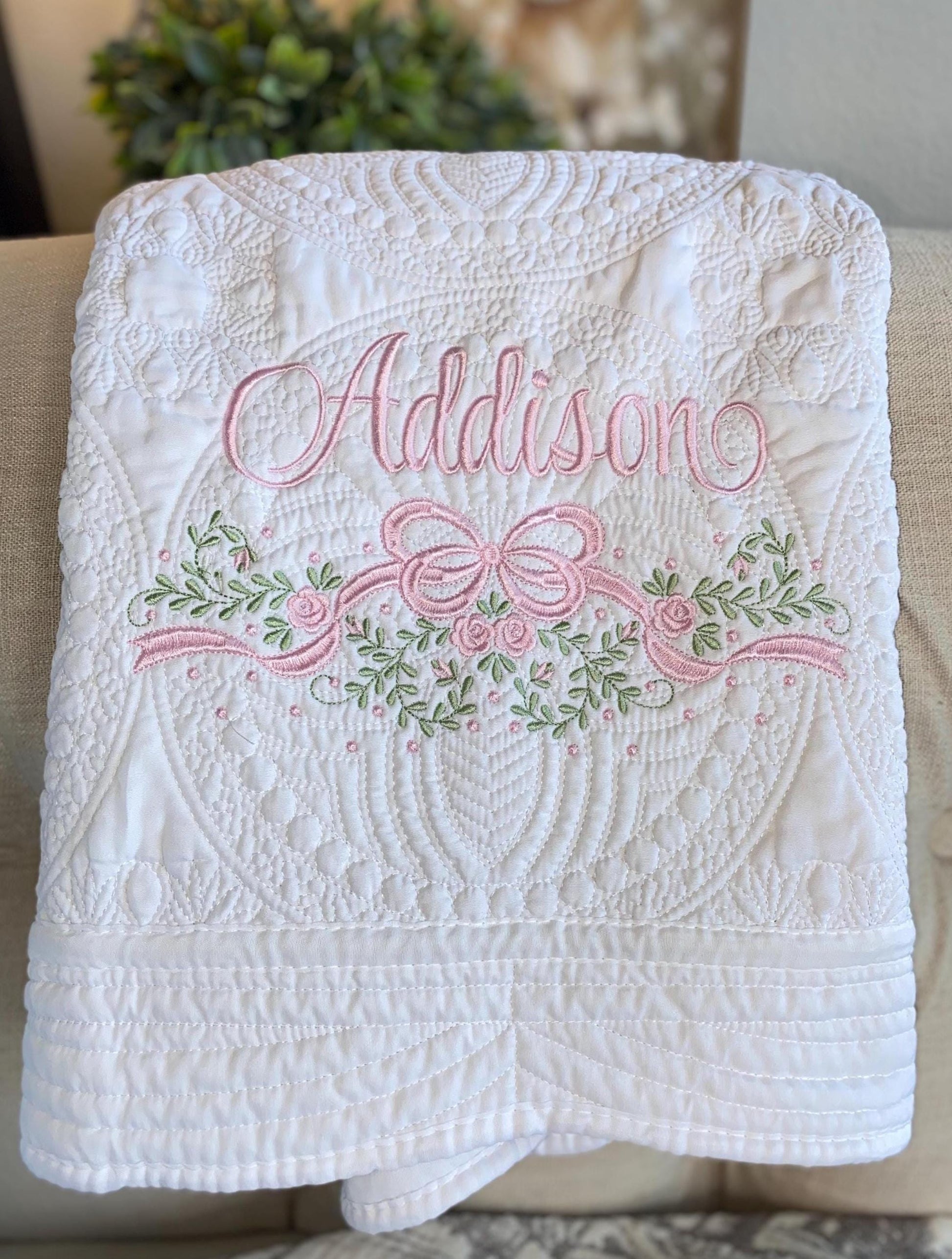 Personalized Embroidered Rose Vine & Bow Baby Quilt | Heirloom Keepsake | Custom Name Blanket featuring delicate pink and green floral embroidery with the name Addison on a textured white quilt.