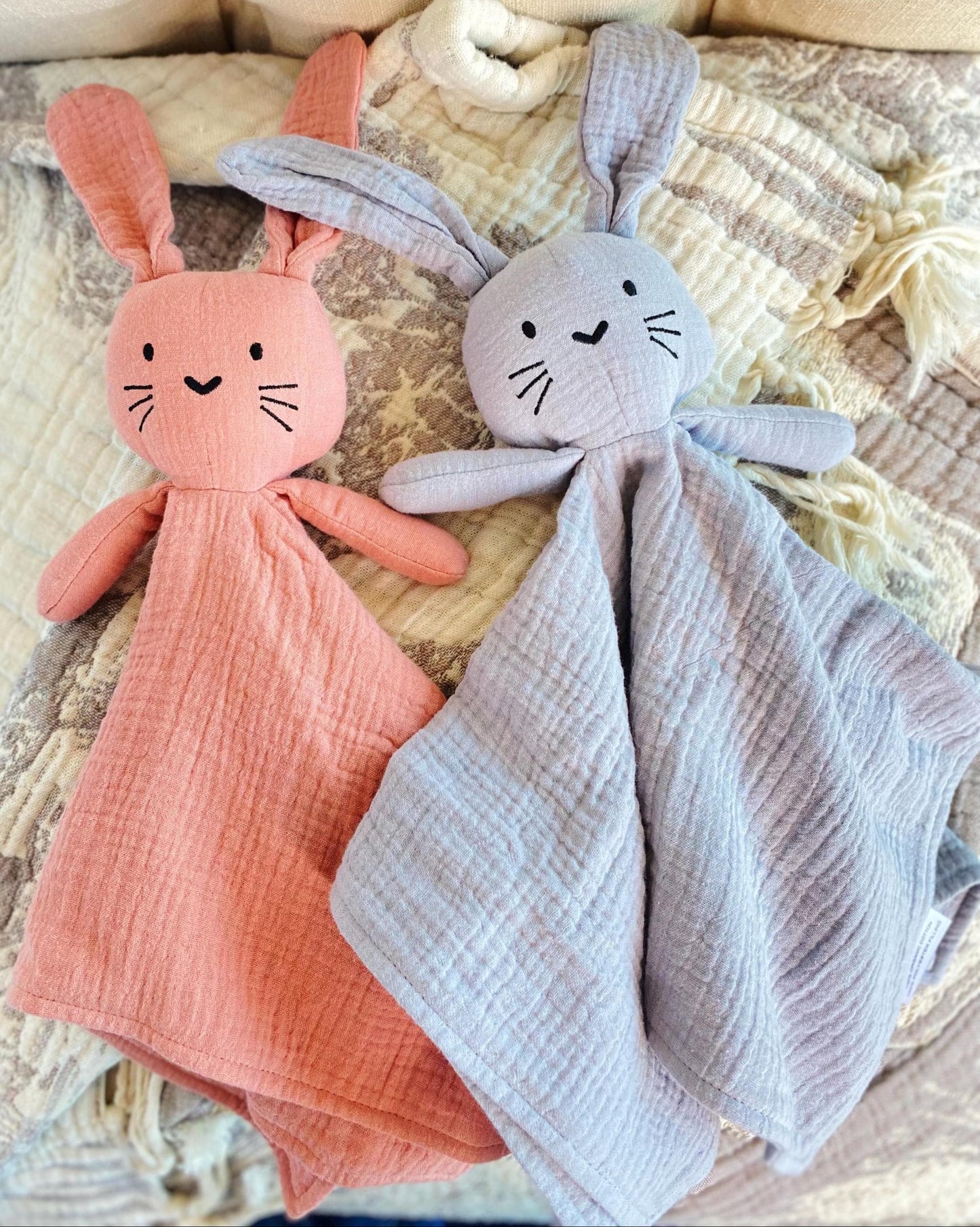 Two soft bunny loveys in pastel pink and light gray made of organic muslin fabric, styled as Personalized Bunny Lovey | Organic Muslin Baby Security Blanket | Custom Embroidered Name, ideal as a handmade baby shower gift.